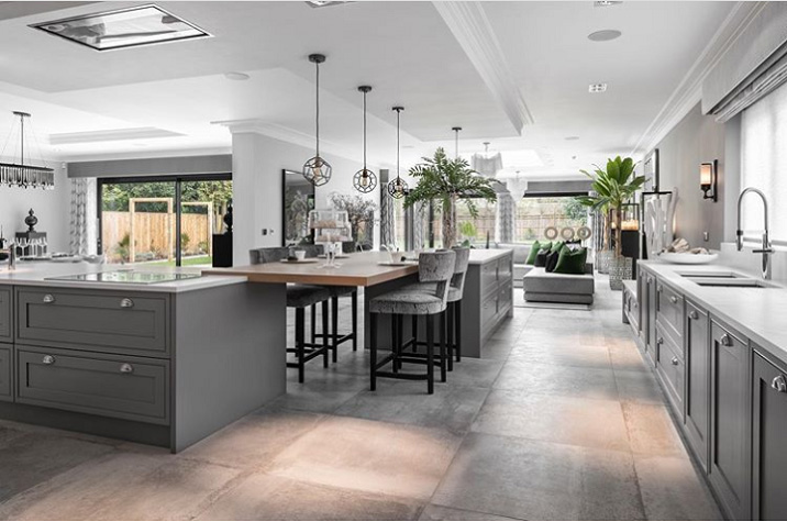 Сocinas abiertas modernas están de moda. Una cocina moderna y abierta al salon fue diseñada en colores blancos, gris y marrón claro. Foto de una cocina gris y madera.
