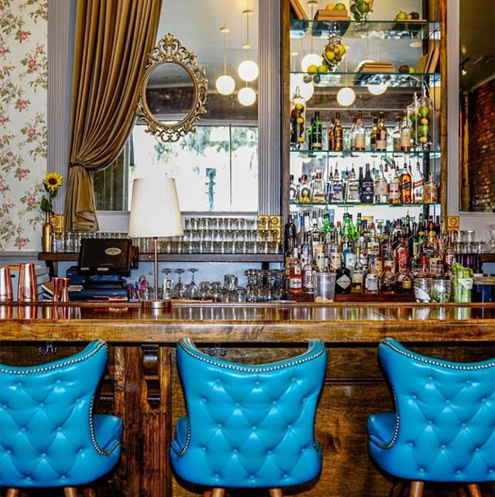Un bar diseñado con espejos y sillas azules, con tapicero de capitoné. Proyectos de interiorismo para bares. Diseño de restaurantes rústicos. Bares de diseño. Diseño de restaurantes pequeños.