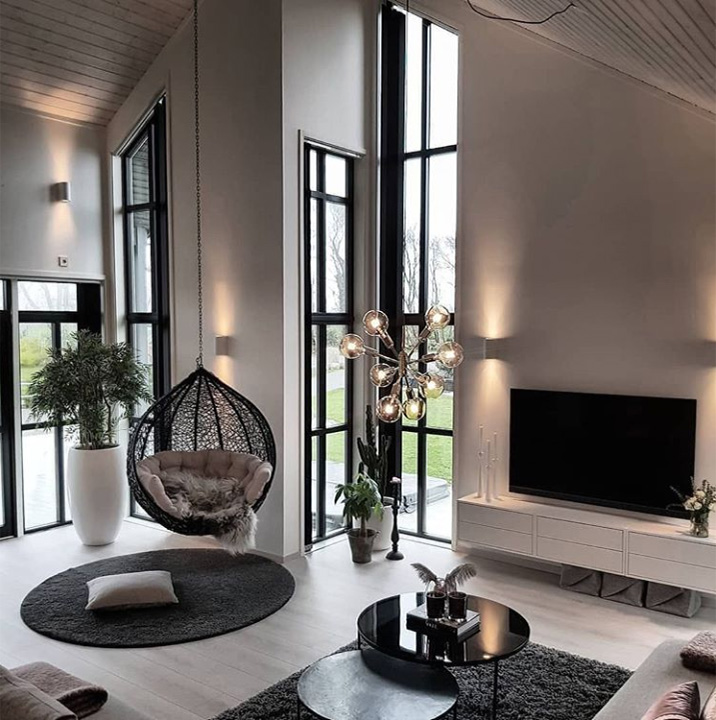 Интерьер гостинной в современном скандинавском доме с камином и подвесным креслом. 
 Уютная гостиная со скандинавским дизайном.