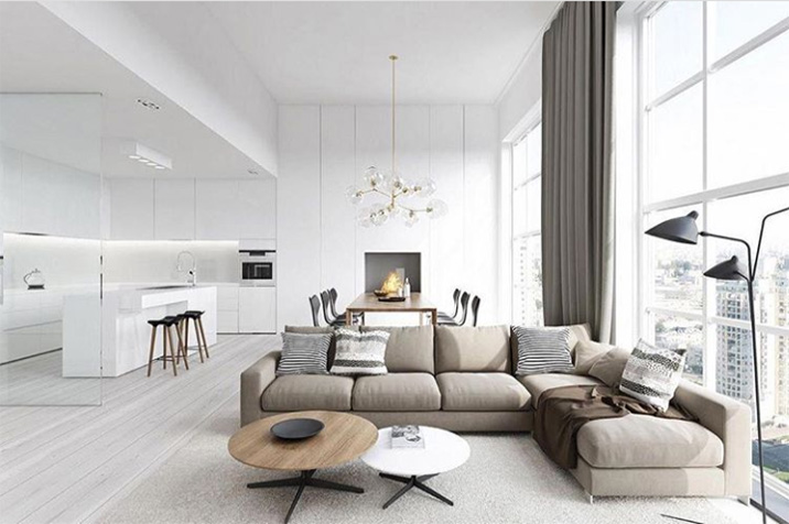 Una sala de estar totalmente blanca de decoración escandinava. Una cocina moderna blanca abierta al salón con un sofá esquinero. Una zona de comedor en un espacio nórdico.