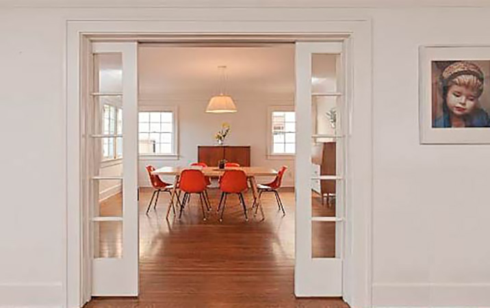 Una puerta corredera ancha que divide la sala de estar y un comedor enorme con sillas rojas. Un interior en color blanco con toques rojos.